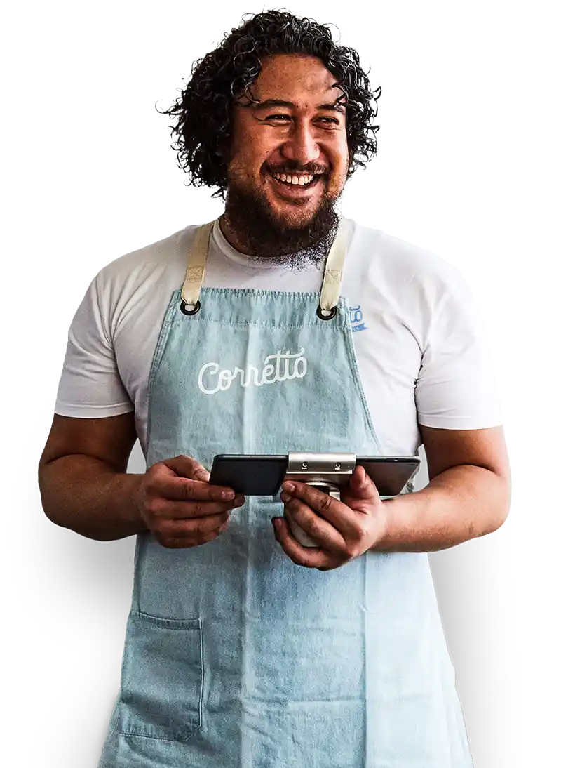 Ein lächelnder Restaurantbesitzer in einem weissen T-Shirt und einer Markenschürze verwendet Lightspeed Restaurant auf einem Tablet.