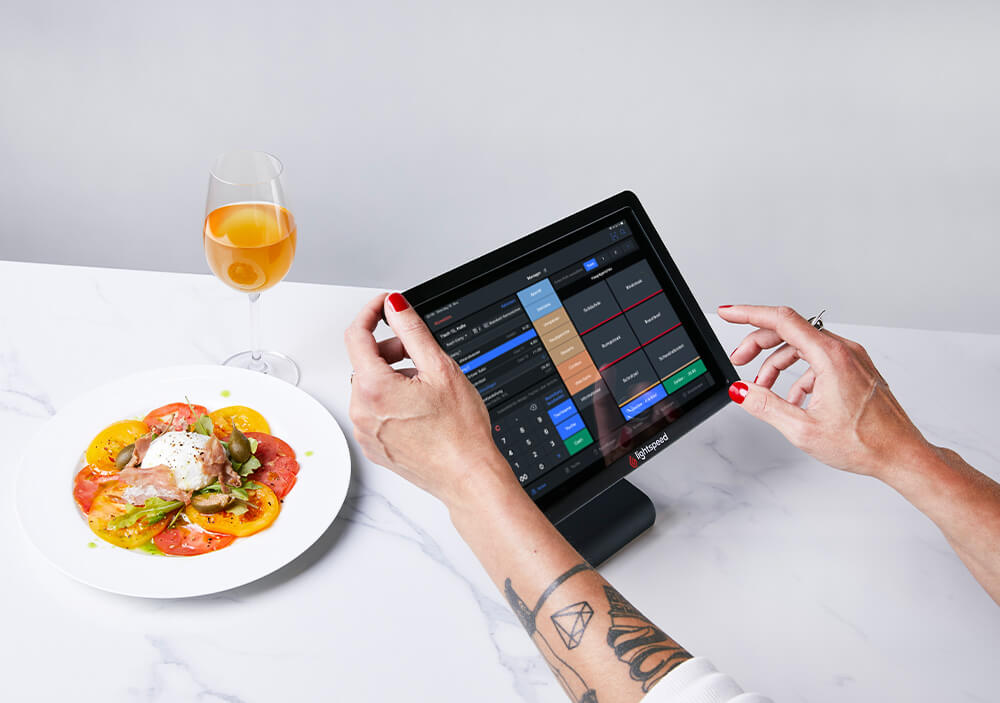 iPad-Kassensystem wird von einem Mitarbeiter bedient während ein Gericht serviert wird